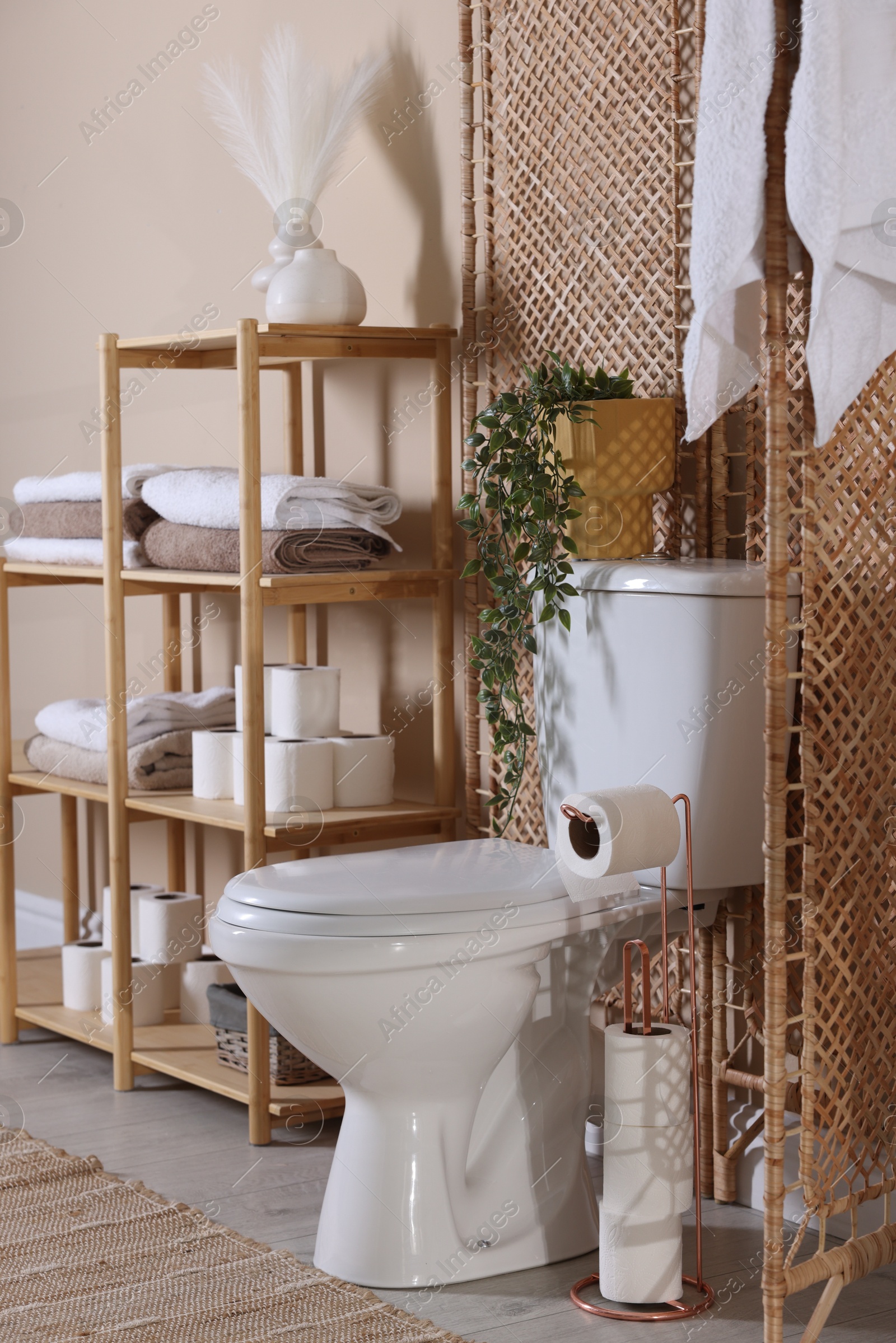 Photo of Ceramic toilet bowl, folding screen and necessities in restroom