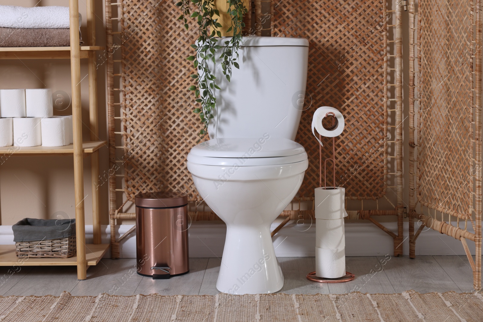 Photo of Ceramic toilet bowl, folding screen and necessities in restroom