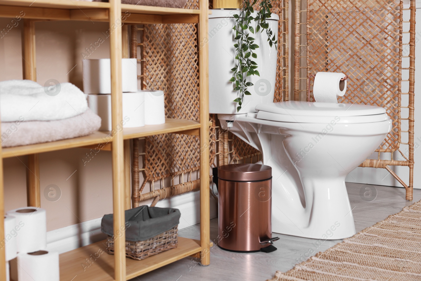 Photo of Ceramic toilet bowl, folding screen and necessities in restroom