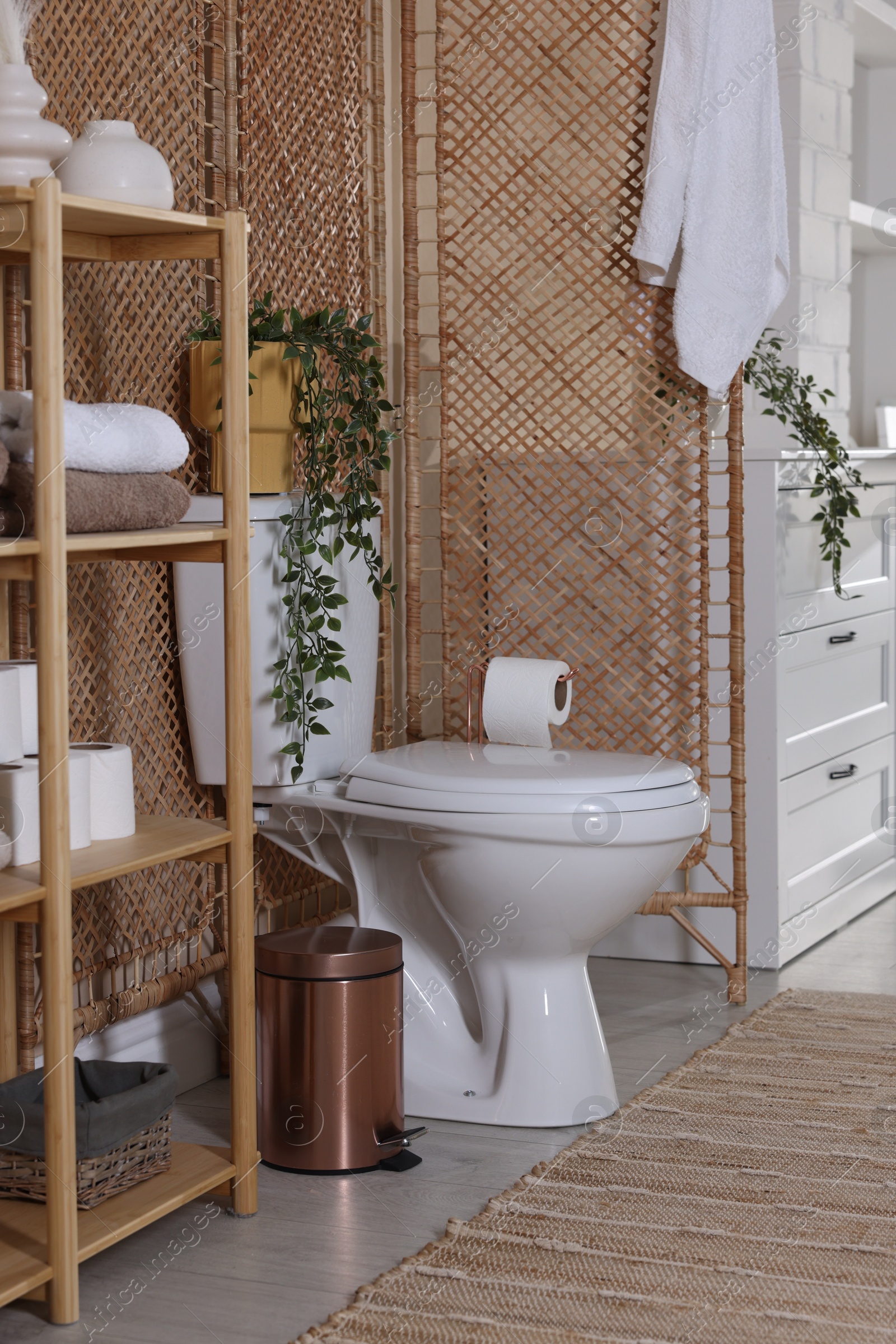 Photo of Ceramic toilet bowl, folding screen and necessities in restroom