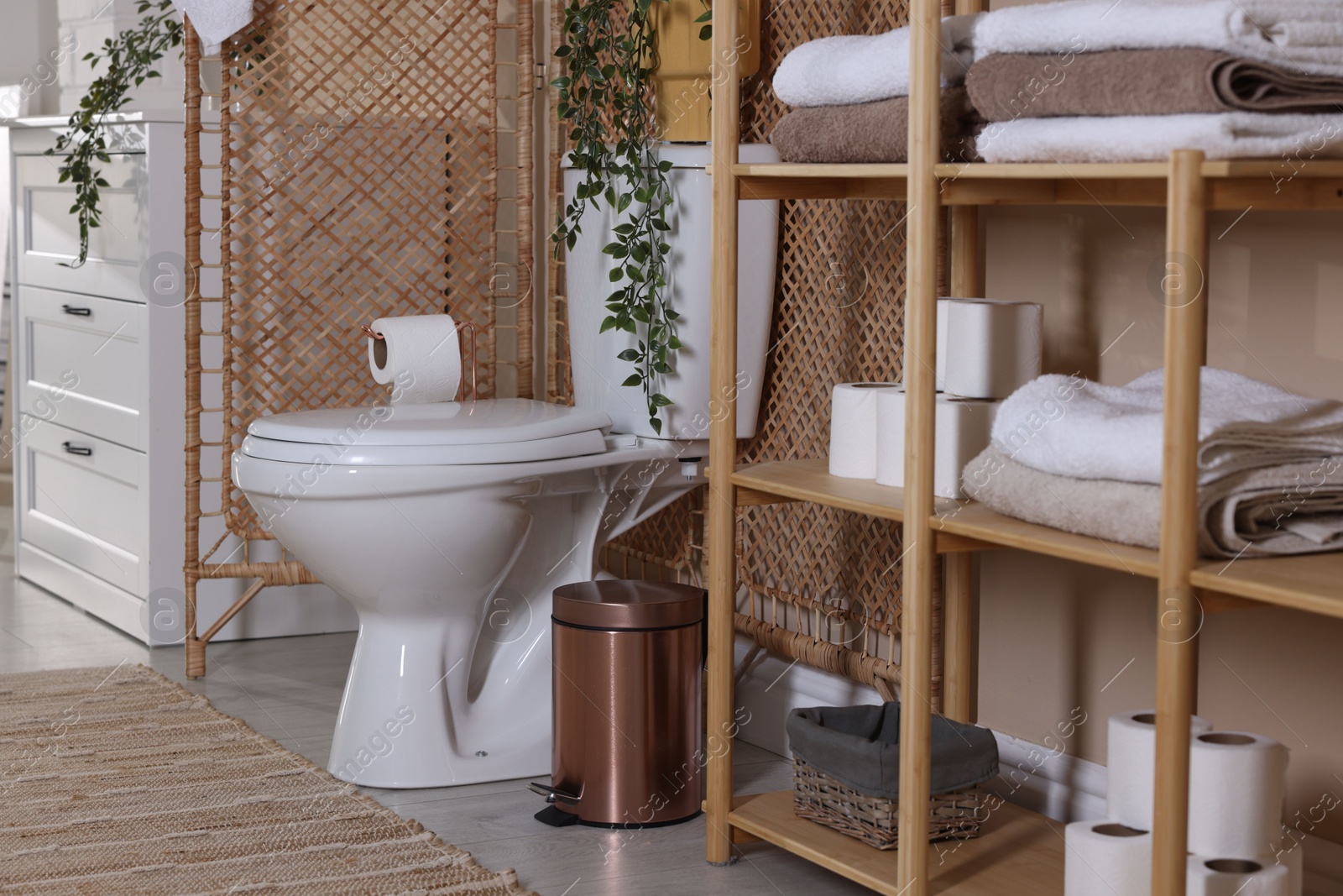 Photo of Ceramic toilet bowl, folding screen and necessities in restroom