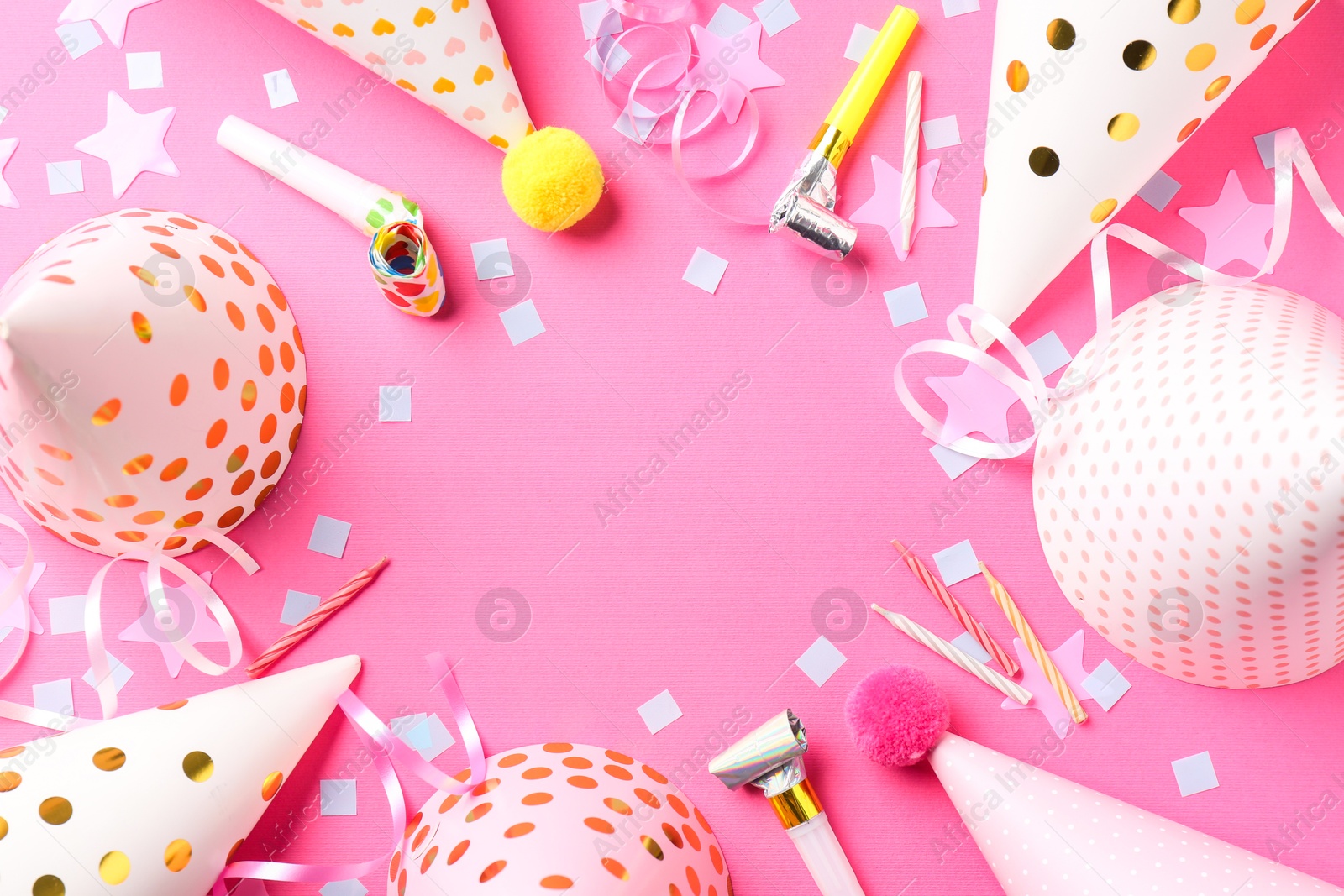 Photo of Frame of party hats, horns, streamers and confetti on pink background, flat lay. Space for text