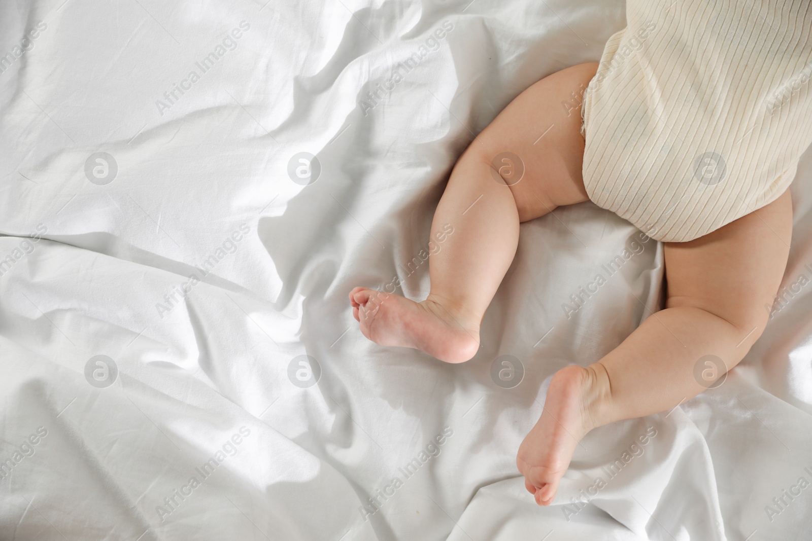 Photo of Cute little baby on bed indoors, top view. Space for text