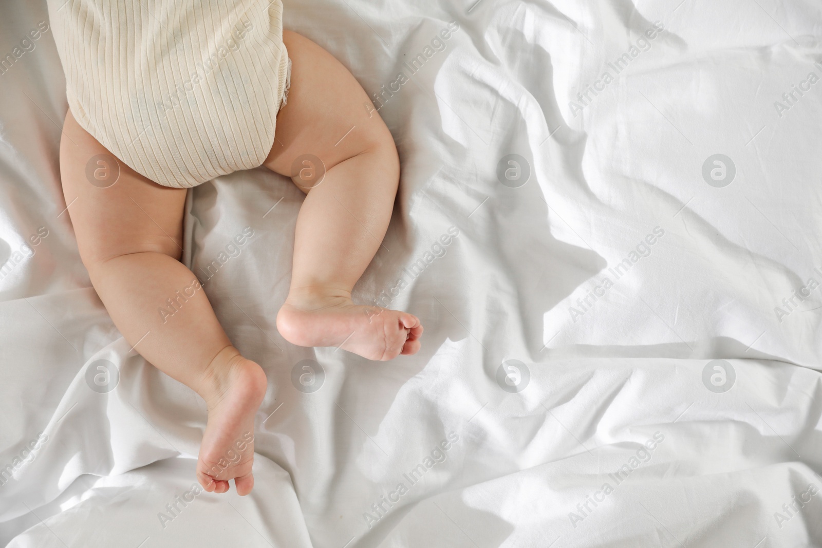 Photo of Cute little baby on bed indoors, top view. Space for text