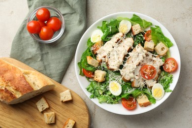 Photo of Tasty Caesar salad with chicken, bread and tomatoes in bowl on gray textured table, flat lay