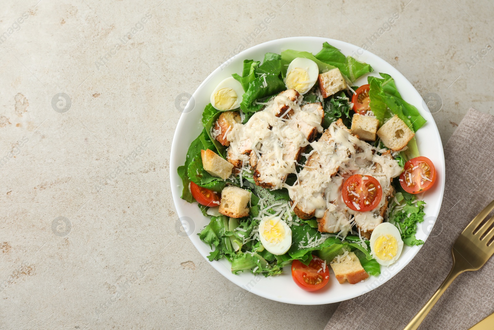 Photo of Tasty Caesar salad with chicken and tomatoes in bowl served on gray textured table, flat lay. Space for text