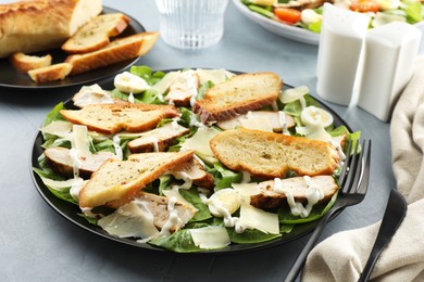 Photo of Delicious Caesar salad with chicken on grey textured table, closeup