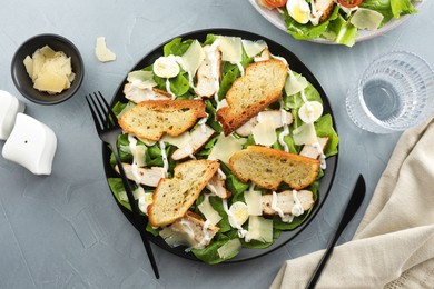 Photo of Delicious Caesar salad with chicken served on grey textured table, flat lay