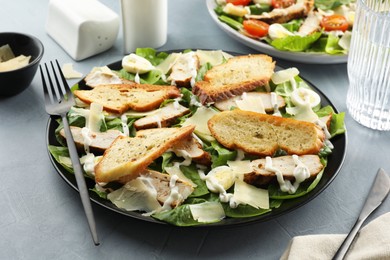 Photo of Delicious Caesar salad with chicken on grey textured table