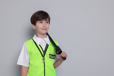 Photo of Boy pretending to be policeman on light grey background, space for text. Dreaming of future profession