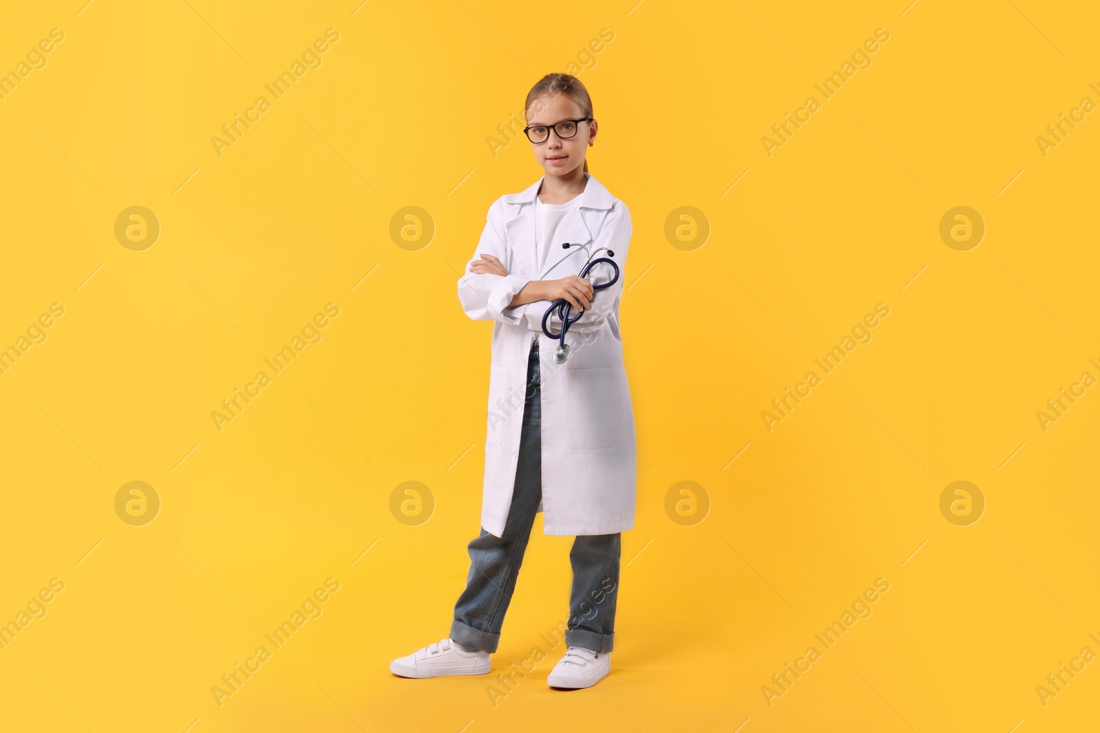 Photo of Girl with stethoscope pretending to be doctor on yellow background. Dreaming of future profession