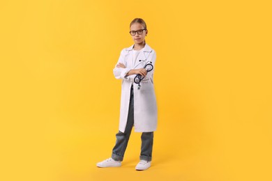 Girl with stethoscope pretending to be doctor on yellow background. Dreaming of future profession