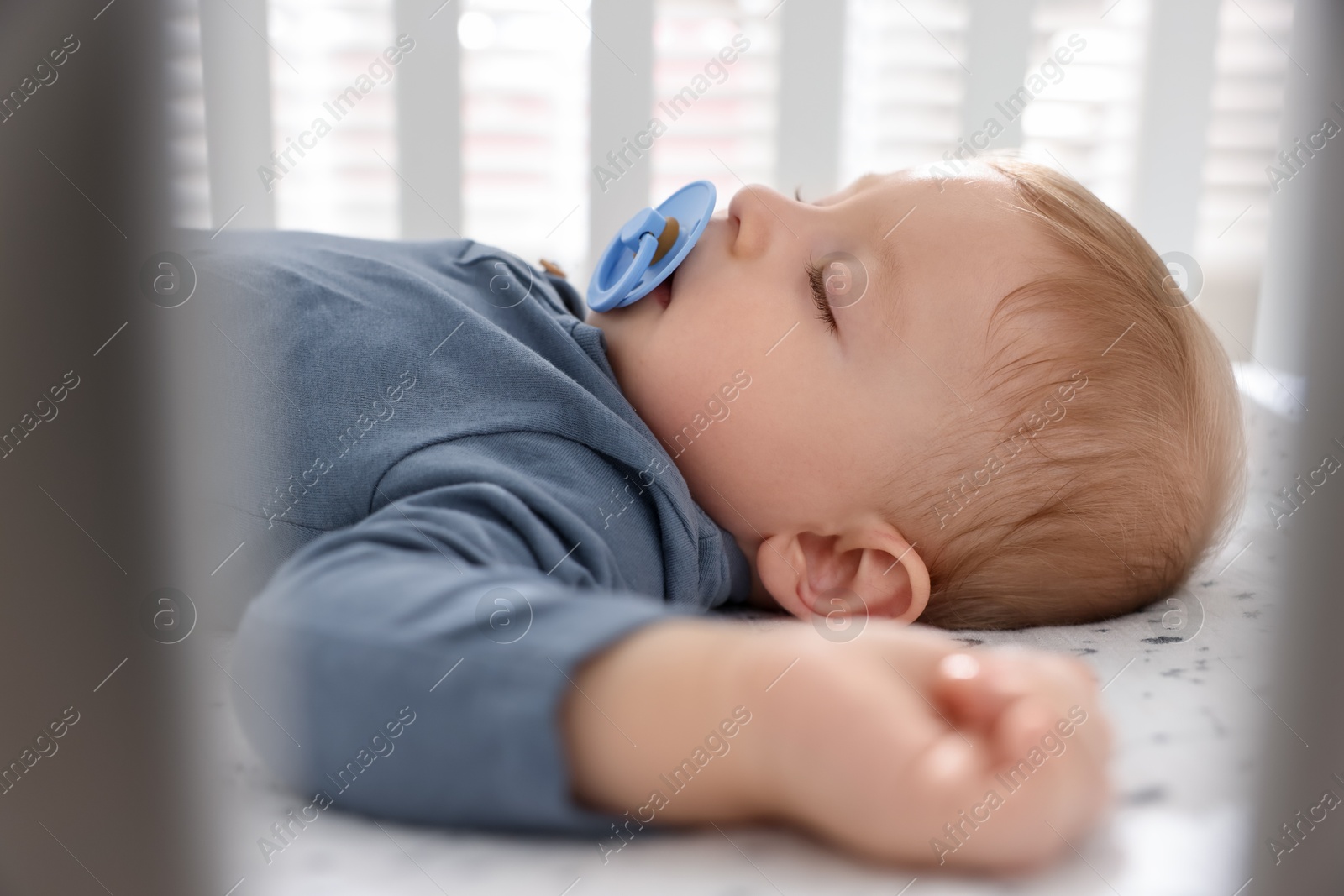 Photo of Cute baby sleeping in crib at home, closeup