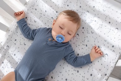 Photo of Cute baby sleeping in crib at home, top view