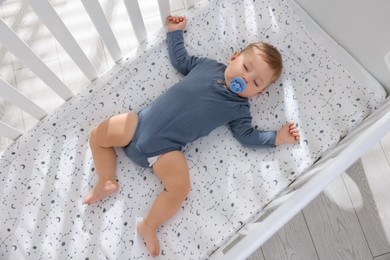 Cute baby sleeping in crib at home, top view