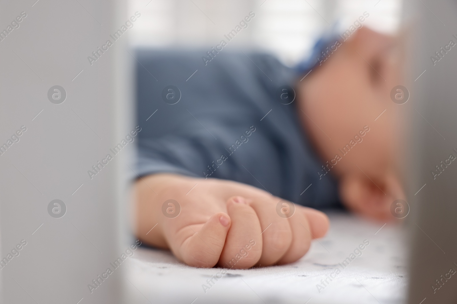 Photo of Cute baby sleeping in crib at home, closeup. Selective focus