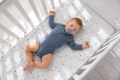 Cute baby sleeping in crib at home, top view