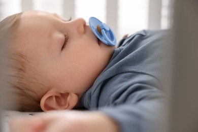 Photo of Cute baby sleeping in crib at home, closeup