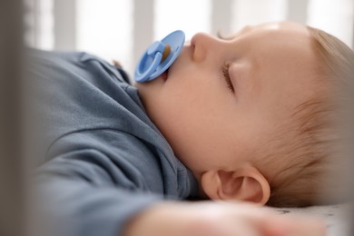 Photo of Cute baby sleeping in crib at home, closeup