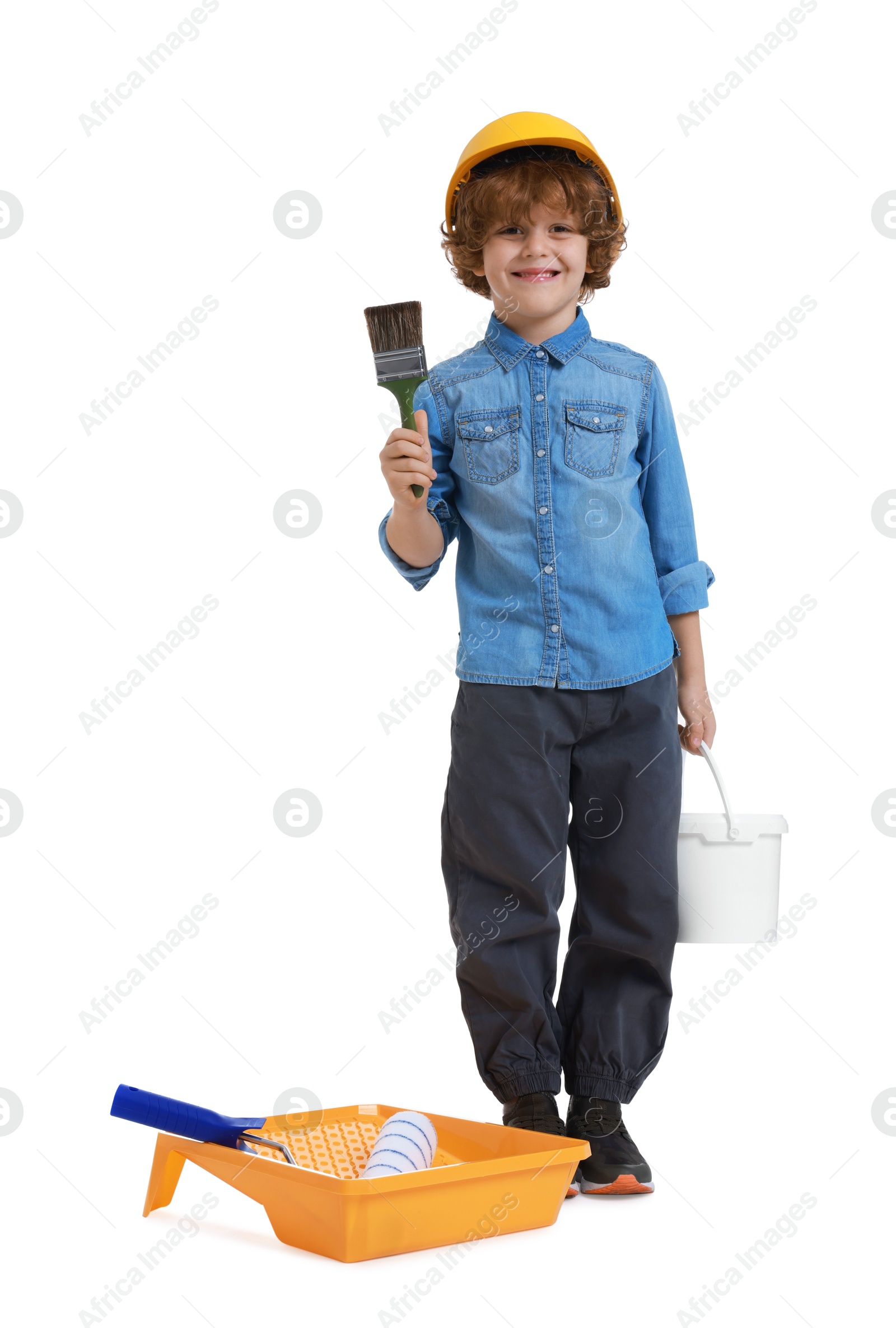 Photo of Little boy in hard hat with different painting tools on white background. Dreaming about future profession