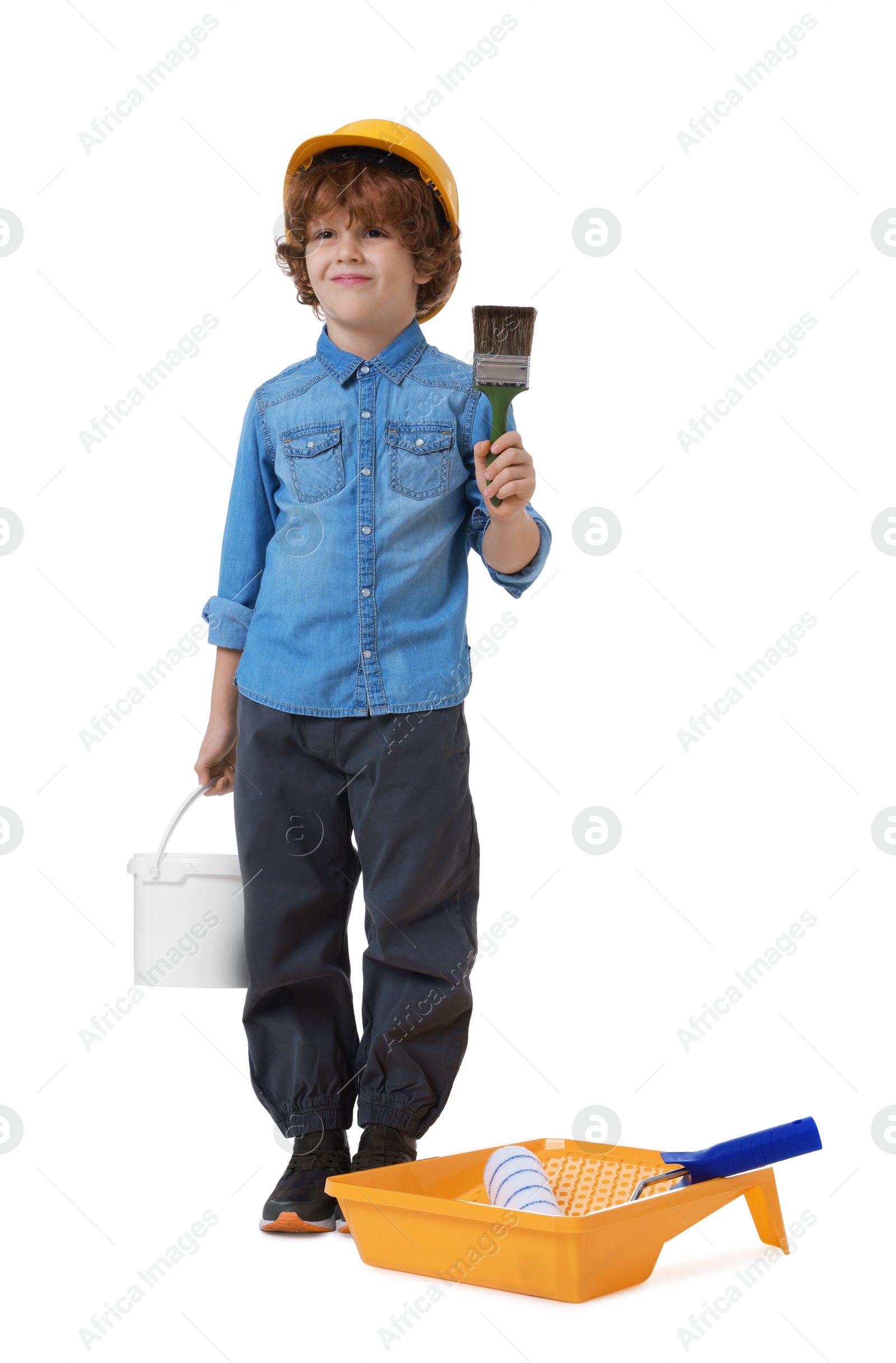 Photo of Little boy in hard hat with different painting tools on white background. Dreaming about future profession