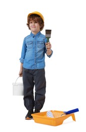 Photo of Little boy in hard hat with different painting tools on white background. Dreaming about future profession