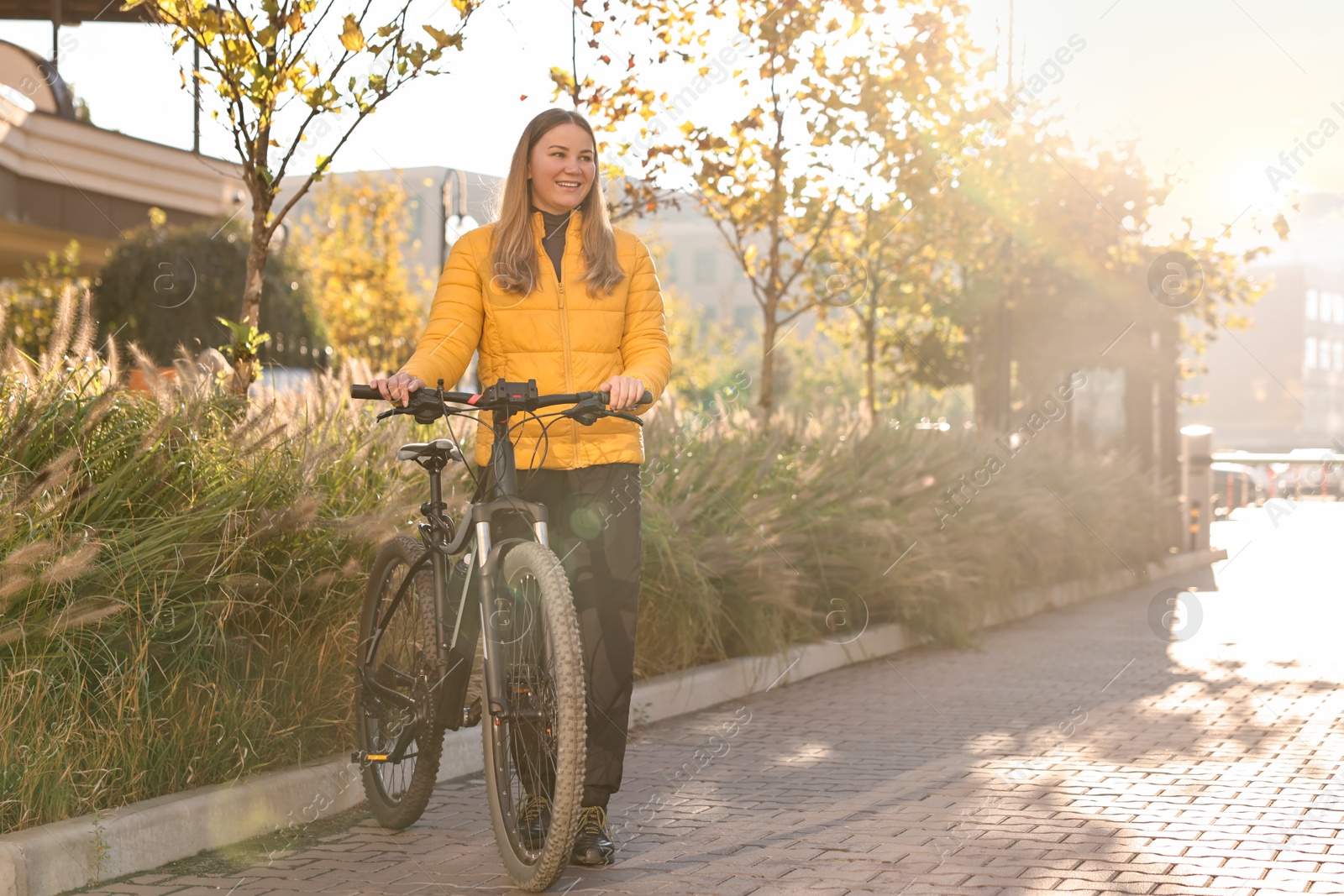 Photo of Smiling woman with bicycle outdoors on sunny day