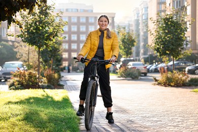 Photo of Smiling woman with bicycle outdoors on sunny day