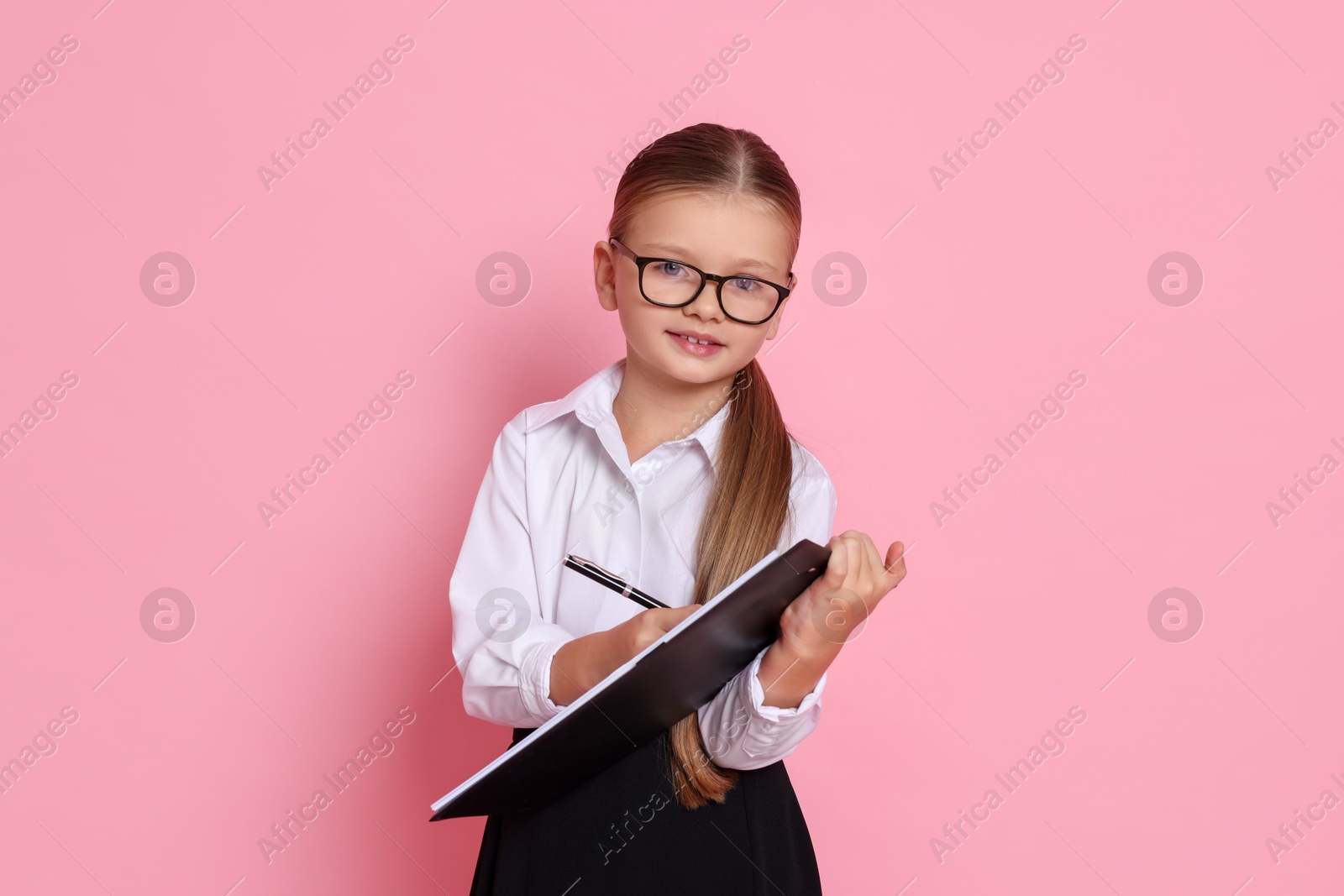 Photo of Little girl with clipboard pretending to be accountant on pink background. Dreaming of future profession