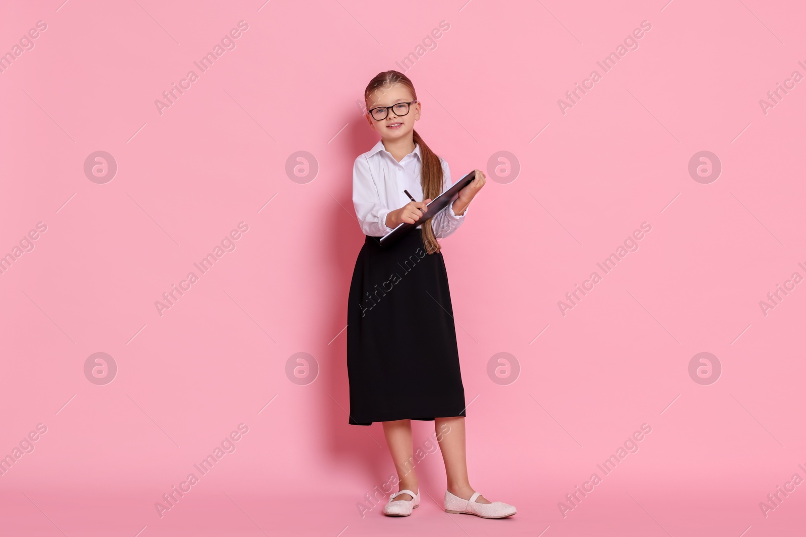 Photo of Little girl with clipboard pretending to be accountant on pink background. Dreaming of future profession