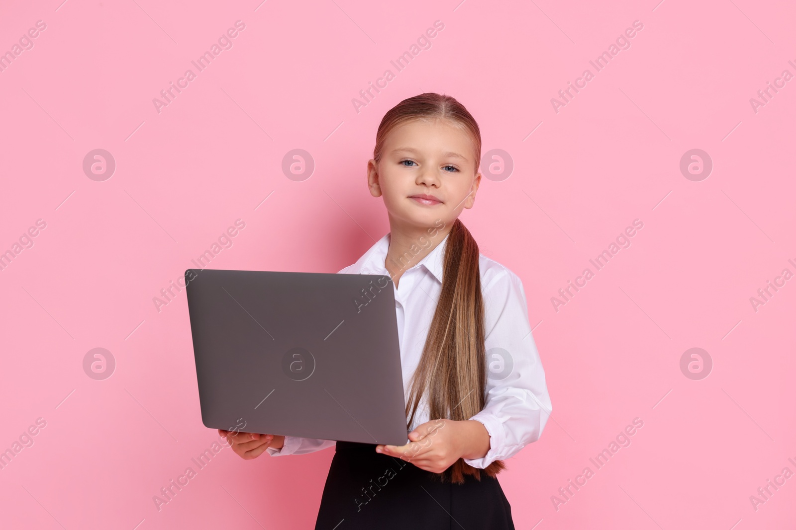 Photo of Little girl with laptop pretending to be accountant on pink background. Dreaming of future profession