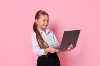 Photo of Little girl with laptop pretending to be accountant on pink background. Dreaming of future profession