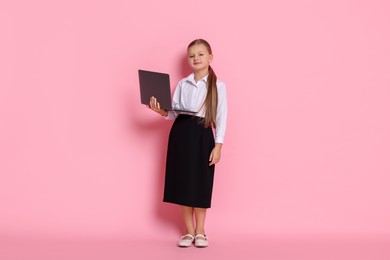 Photo of Little girl with laptop pretending to be accountant on pink background. Dreaming of future profession