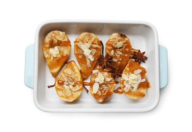 Photo of Delicious pears with caramel sauce, almond flakes and anise stars in baking dish isolated on white, top view