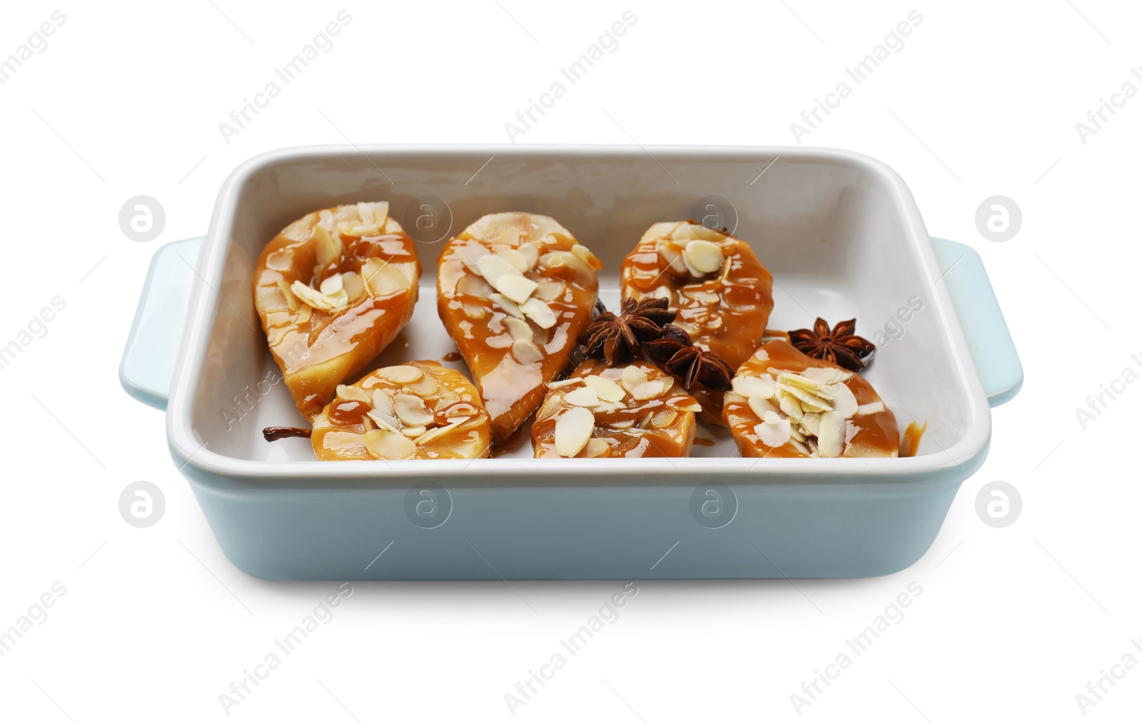 Photo of Delicious pears with caramel sauce, almond flakes and anise stars in baking dish isolated on white