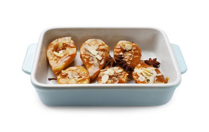 Photo of Delicious pears with caramel sauce, almond flakes and anise stars in baking dish isolated on white