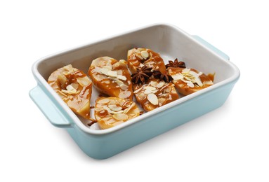 Photo of Delicious pears with caramel sauce, almond flakes and anise stars in baking dish isolated on white