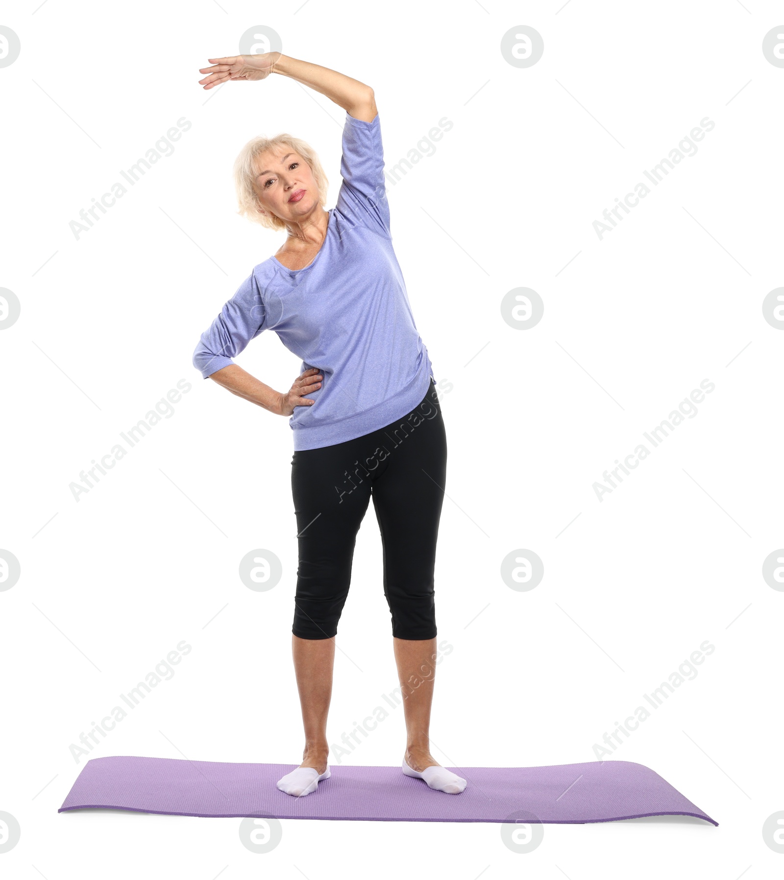 Photo of Senior woman exercising with fitness mat on white background