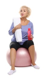 Photo of Senior woman with fitness ball, towel and water on white background