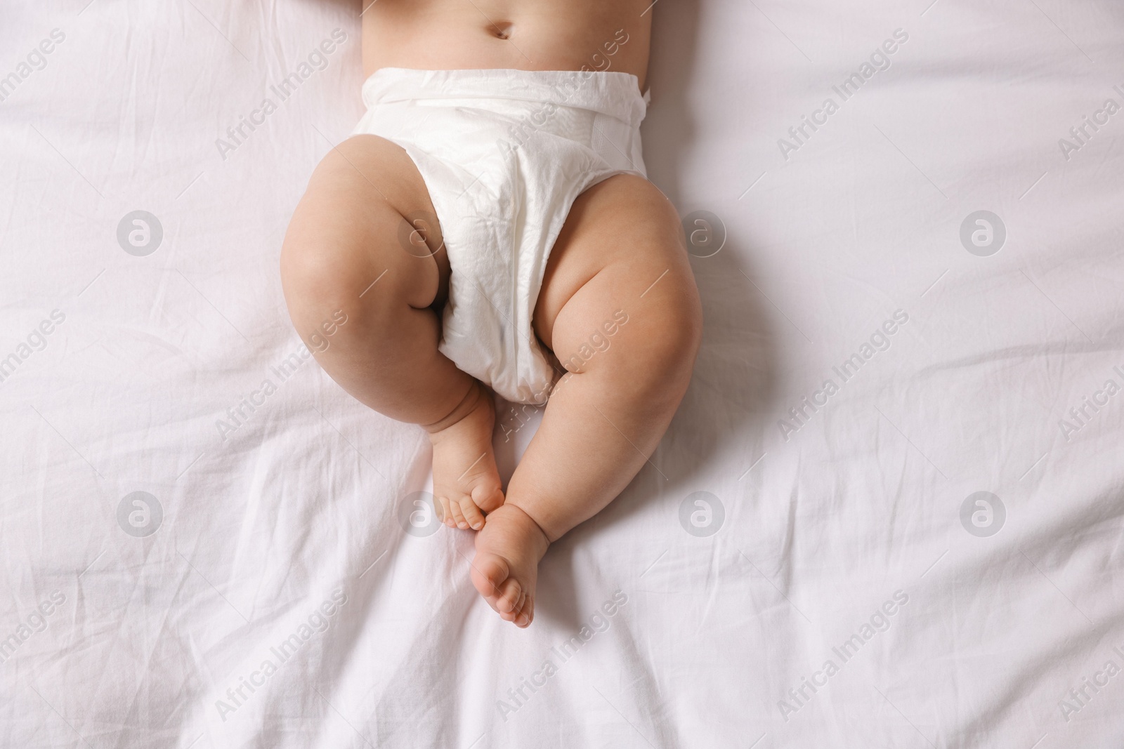 Photo of Cute little baby in diaper on bed, top view