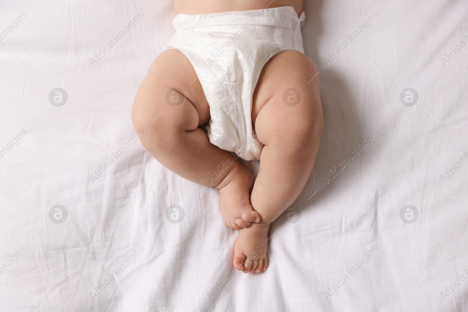 Photo of Cute little baby in diaper on bed, top view