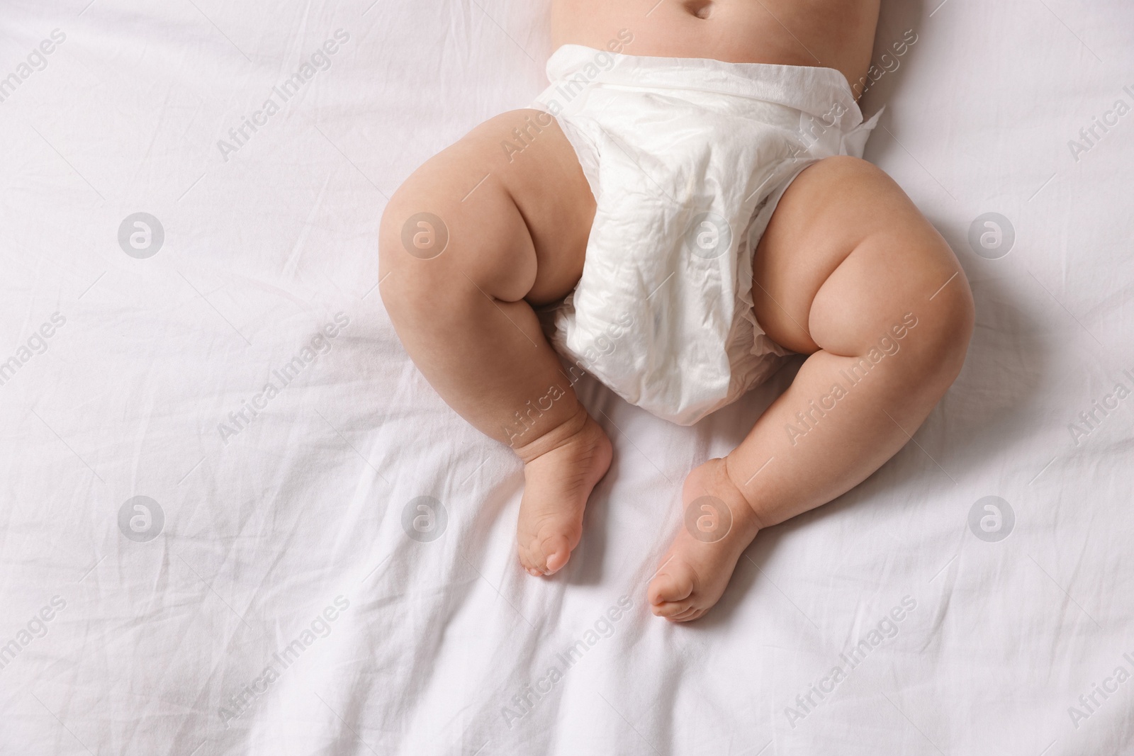 Photo of Cute little baby in diaper on bed, top view