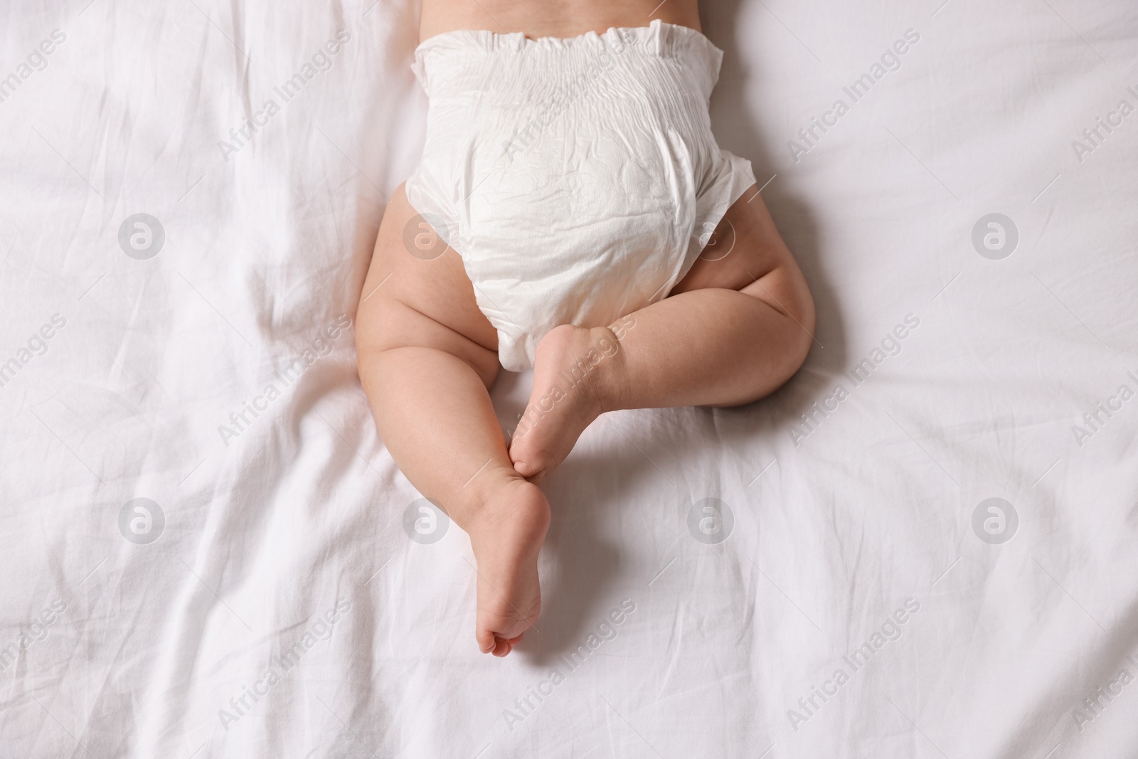 Photo of Cute little baby in diaper on bed, top view