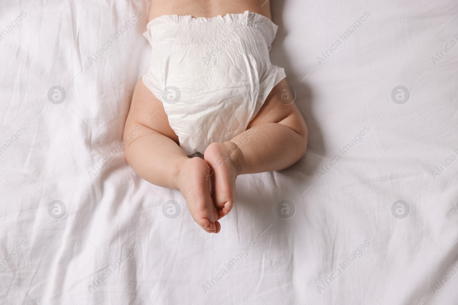 Photo of Cute little baby in diaper on bed, top view