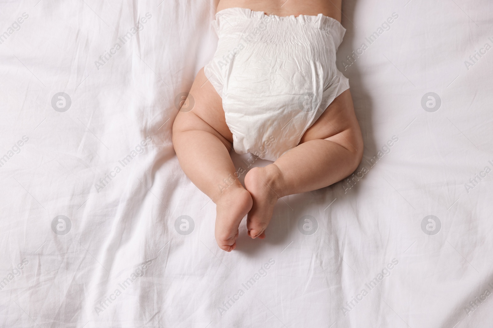 Photo of Cute little baby in diaper on bed, top view