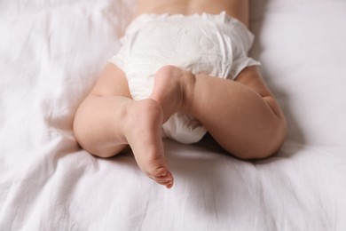 Cute little baby in diaper on bed, closeup