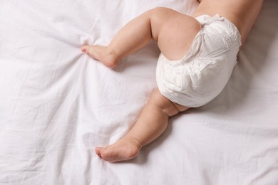 Photo of Cute little baby in diaper on bed, top view