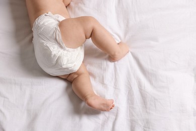 Photo of Cute little baby in diaper on bed, top view