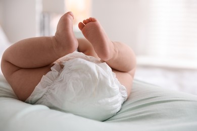 Cute little baby in diaper on bed indoors, closeup