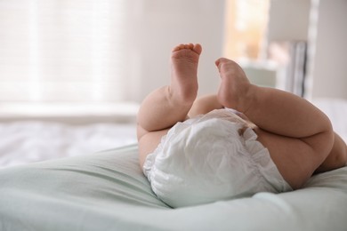 Photo of Cute little baby in diaper on bed indoors, closeup. Space for text